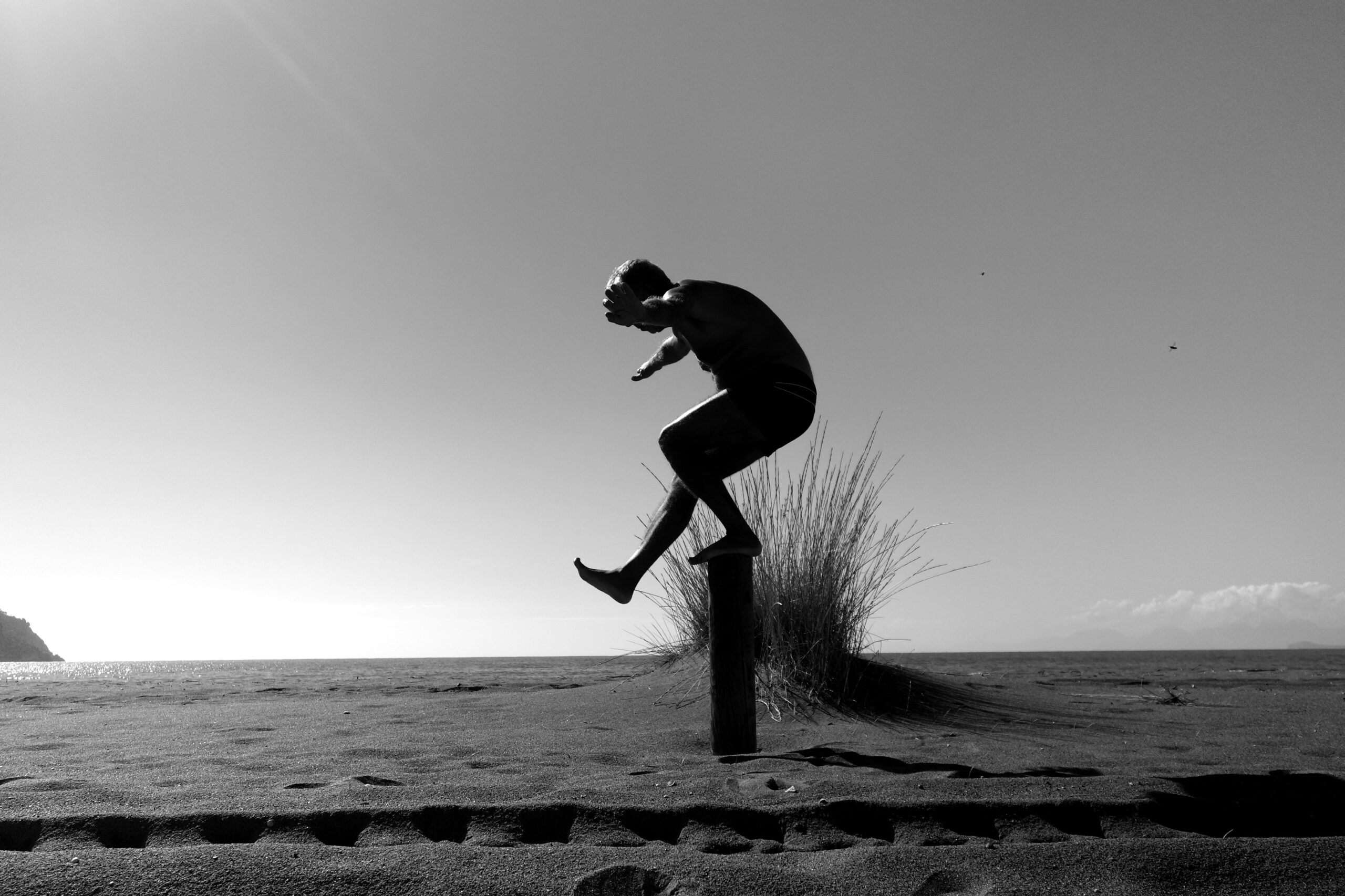 Person jumping from a post on a beach, symbolising overcoming obstacles, resilience, and progress through challenges in hardware development and innovation.